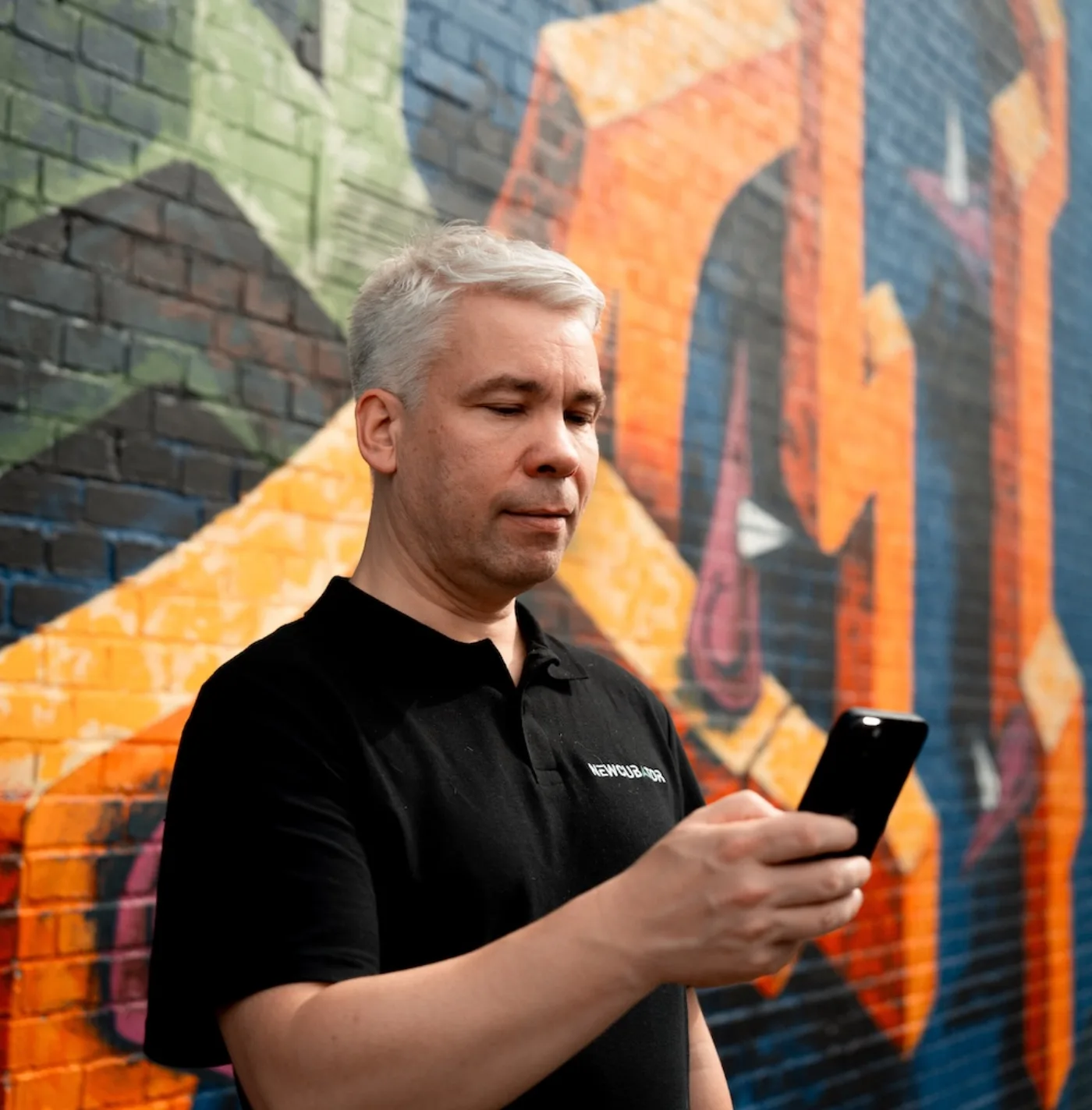 StadtQUEST Nutzer mit Smartphone vor einer urbanen Wandgestaltung