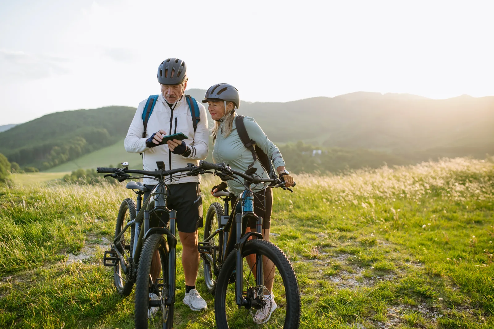 Paar mit E-Bikes informiert sich bei einer Pause am mobilen Gerät